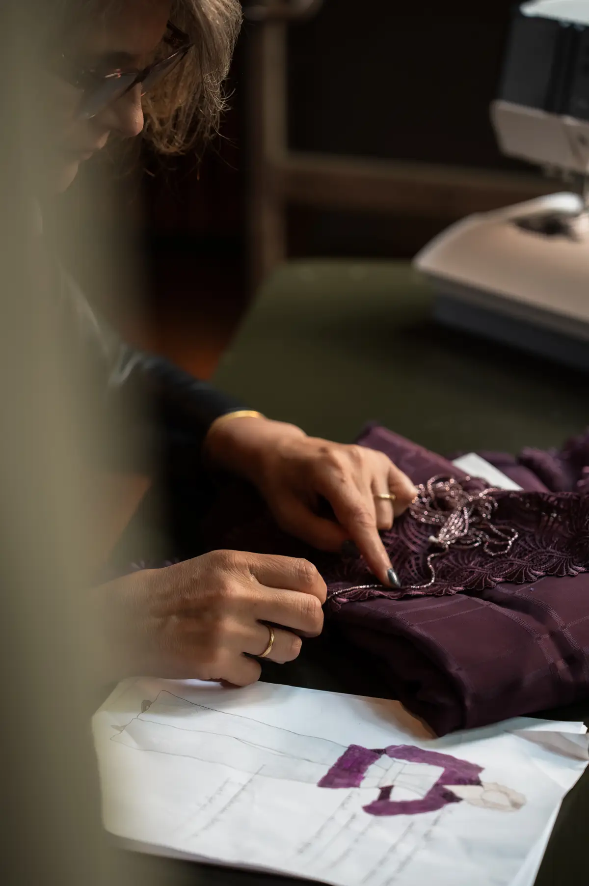 Desiree de Kort controleert paarse kantstof met modeontwerpschets in een atelier