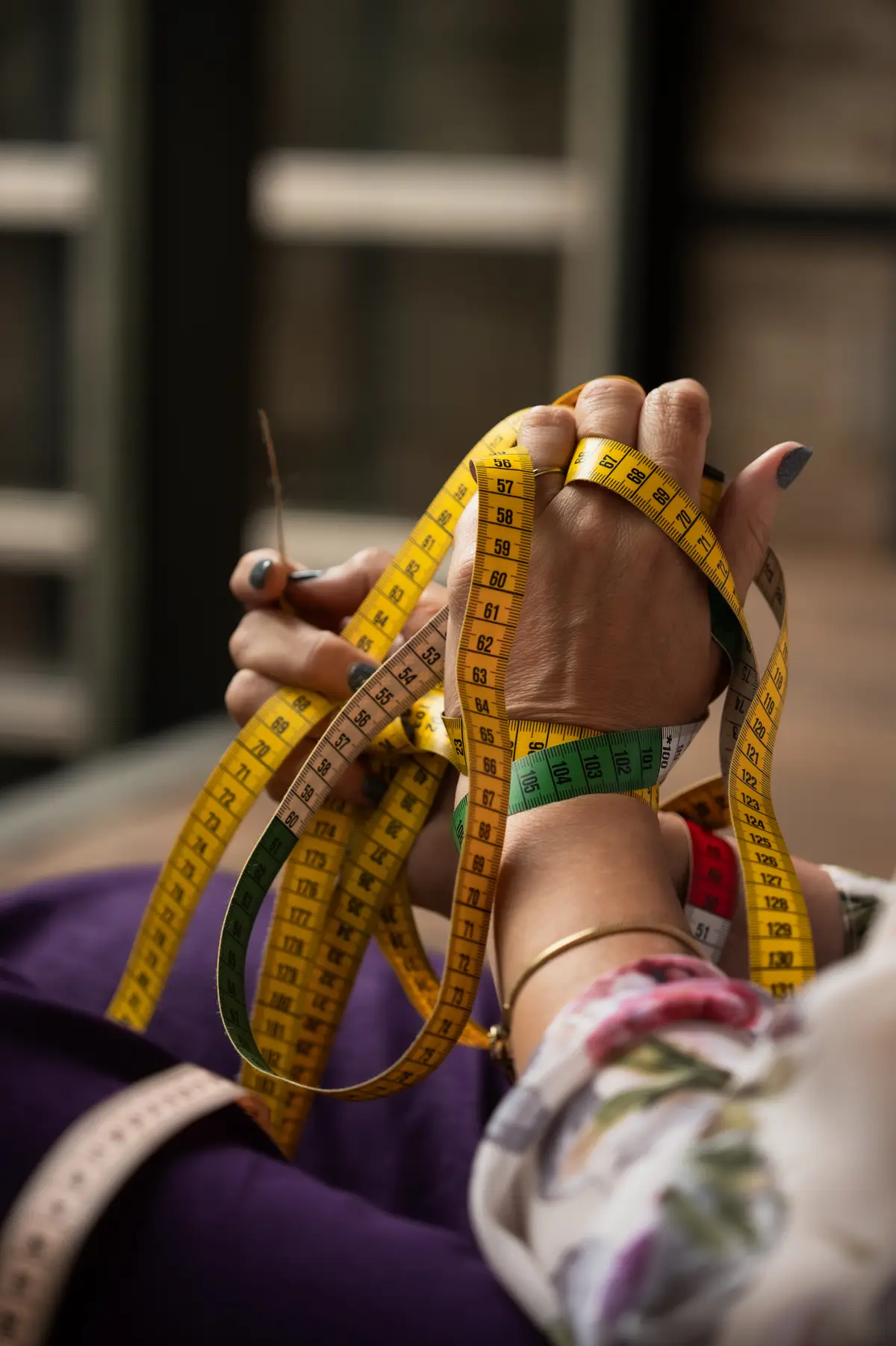 Handen met gele meetlinten in een creatieve ontwerpomgeving